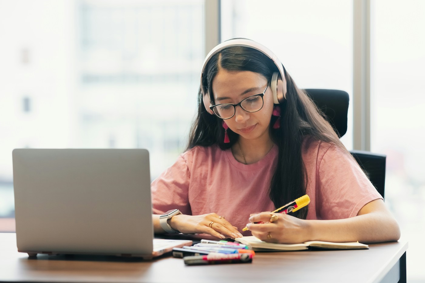 Người học đeo tai nghe, ghi chép bên máy tính